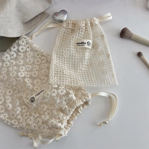 Detail view of mesh lace drawstring storage bag with delicate daisy floral embroidery