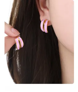 Detailed close-up of pink enamel double-layer C-shaped stud earrings in gold-tone titanium