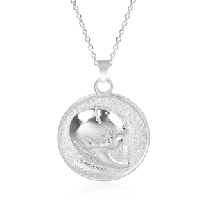 Macro detail of silver stainless steel round pendant featuring an embossed skull carving