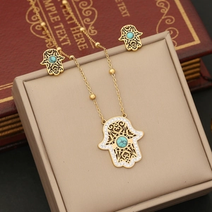 Detail of Hamsa hand jewelry set with turquoise stone on golden bead chain necklace