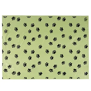Detail view of biodegradable green pet waste bags with black paw print patterns on white background