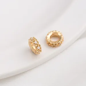 Detail of 14K gold plated beads with cubic zirconia inlay and hollow relief patterns