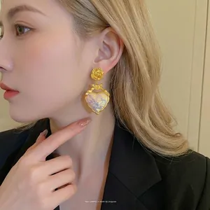 Boucles d'oreilles cœur en résine style vintage français avec détail fleur dorée sur modèle