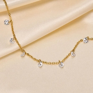 Golden titanium steel anklet with sparkling clear zircon charms on soft beige satin