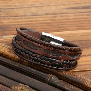 Men's leather feather bracelet with magnetic clasp on a rustic wooden background