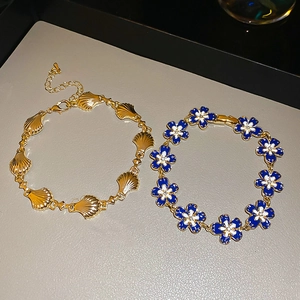 Detailed macro view of gold shell metal bracelet and blue floral enamel jewelry