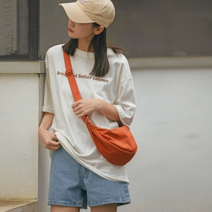Close-up of orange canvas crescent bag showing texture and casual outdoor crossbody style