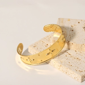 Detail of 18K gold plated open bangle featuring embossed four-leaf clover pattern