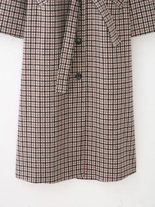 Close-up of plaid wool coat with black buttons and matching waist tie detail
