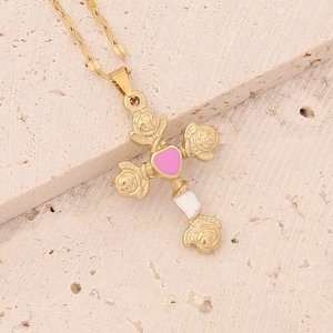 Detailed shot of golden rose cross pendant with pink heart inlay on stone surface