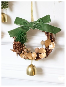Close-up of green velvet bow, pine cones and gold bells on a Christmas wreath hanging