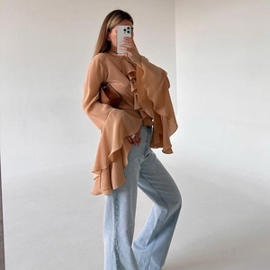 Detail of brown ruffled chiffon shirt with flare sleeves styled with blue jeans