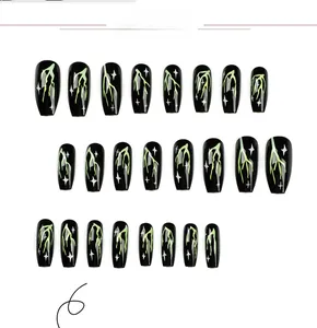 Detailed view of black press-on nails with neon green lightning and white star patterns