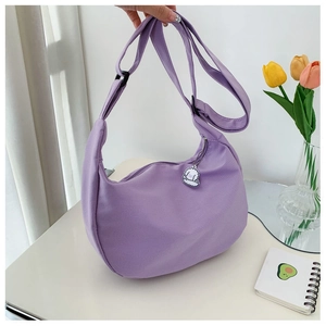 Detail of purple corduroy half-moon bag with adjustable strap and cute dog charm accessory