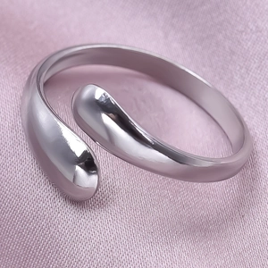 Macro shot of silver teardrop open ring on purple silk fabric background