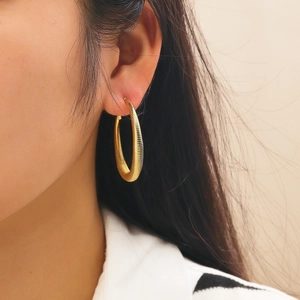 Detailed close-up of chunky gold hoop earrings with vintage textured horizontal stripes