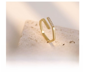 Detailed view of irregular open gold ring with sparkling cubic zirconia on titanium steel
