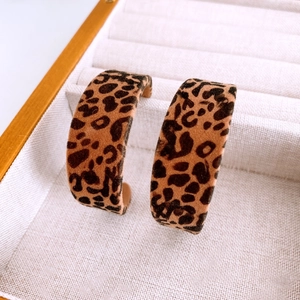 Gros plan de boucles d'oreilles en C à motif léopard floqué sur un plateau à bijoux