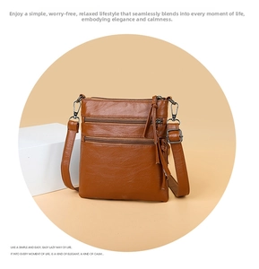 Detail of brown PU leather crossbody bag featuring three front zippers and tassel charms