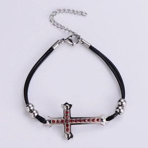 Close-up of black woven bracelet with silver cross pendant and red rhinestones detail