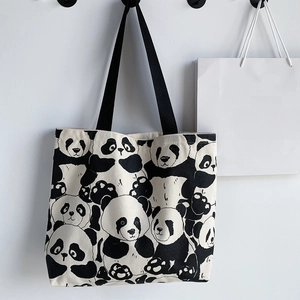 Close-up of durable cream canvas tote bag featuring cute black panda prints and black straps