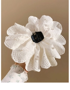 Detail of white lace flower hair claw clip with delicate pearls and layered fabric texture
