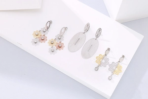 Détail des boucles d'oreilles fleurs ajourées et clous ovales mats avec zircons