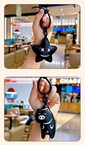 Macro detail of black PU leather star and pig keychains with spring cords and gold charms
