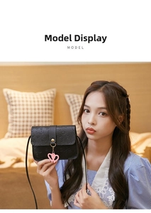 Detail of black embossed PU leather crossbody bag with heart pendant in a cozy setting