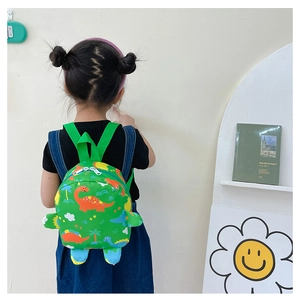 Close-up of cute green cartoon dinosaur backpack worn by a toddler for school or travel