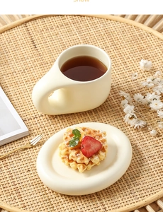 Beige ceramic coffee mug with oval tray set on a rattan plate with lifestyle props