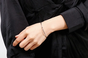 Close-up of minimalist silver stainless steel open bangle with small bead ends on wrist
