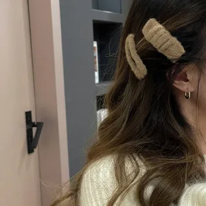 Detail of two-piece brown plush hairpins worn on hair with a warm autumn texture