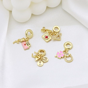 Gold-plated charms with pink enamel and crystals on white silk background