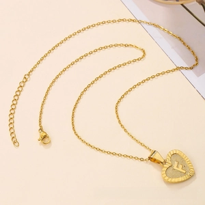 Macro detail of golden heart pendant with engraved letter F on a minimalist cable chain