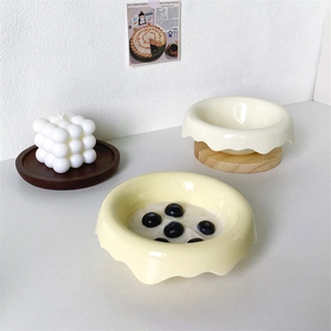 Ceramic bowls with wavy rims on wooden stands featuring yogurt and blueberries breakfast