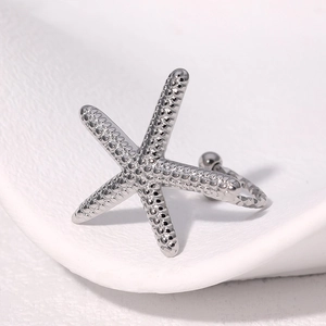 Minimalist silver starfish stainless steel ring with textured bead details on white tray