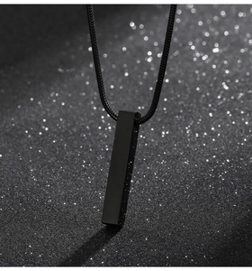 Detailed macro view of black vertical bar pendant with snake chain on dark glitter background