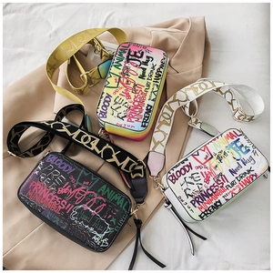 Close-up of street style graffiti crossbody bags in black and white with wide straps