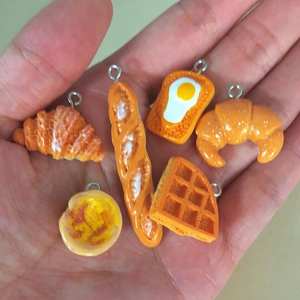 Set of 6 realistic resin food pendants including croissants and toast held in palm
