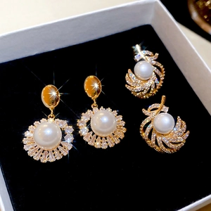 Detailed macro of 18k gold plated pearl drop earrings with sparkling cubic zirconia accents
