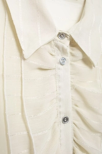 Detail of ruffled collar and buttons on a sheer off-white striped chiffon blouse