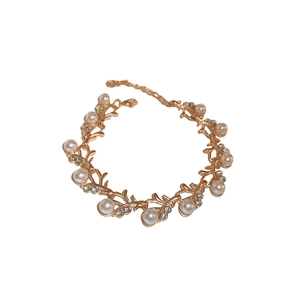 Elegant gold leaf bracelet with round pearls and sparkling rhinestones on white backdrop