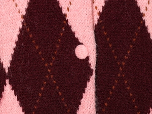 Detailed macro view of argyle diamond knit fabric and pink cloth covered button