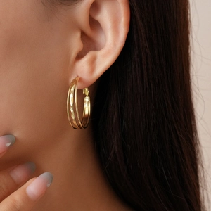 Close-up of layered geometric gold earrings with diamond-cut texture on a model side profile