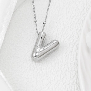 Detailed macro view of a 3D polished silver V-letter pendant on a delicate chain necklace