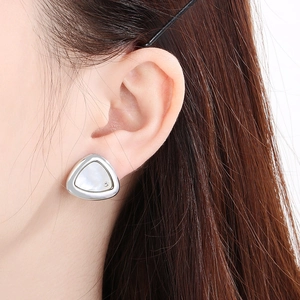 Gros plan sur des boucles d'oreilles triangles avec nacre et diamant sur le mannequin