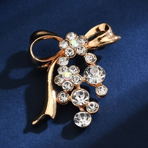 Close-up of golden bow brooch with sparkling rhinestones on dark blue background