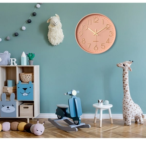 Detail of pink wall clock with gold 3D numbers in a cozy nursery room setting