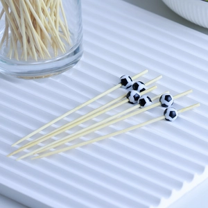 Detailed view of bamboo fruit picks featuring black and white soccer ball toppers on a tray